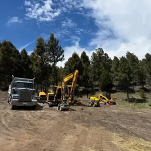 Site preparation Butte MT excavation equipment and dump truck preparing a dirt work site in a wooded area near Butte, Montana.