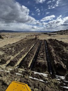 Septic system installation with exposed tank and drain field before backfilling in Montana