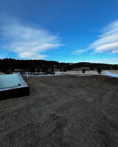 Residential excavation site prepared for new home foundation in Montana with leveled grading and trenching completed.